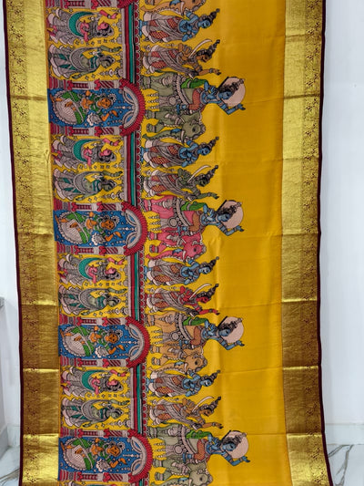 Decorative saree with intricate patterns on a yellow background, displayed indoors.